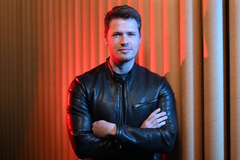 James Sackl, Melbourne founder and writer behind the Golden Age project, in a black leather jacket against a red-lit backdrop.