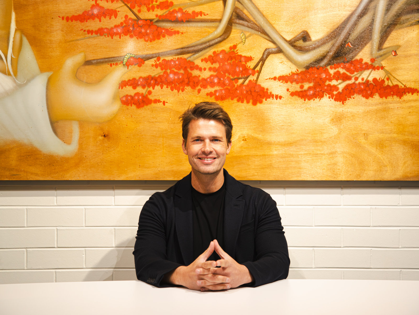 Portrait of James Sackl seated beneath contemporary artwork